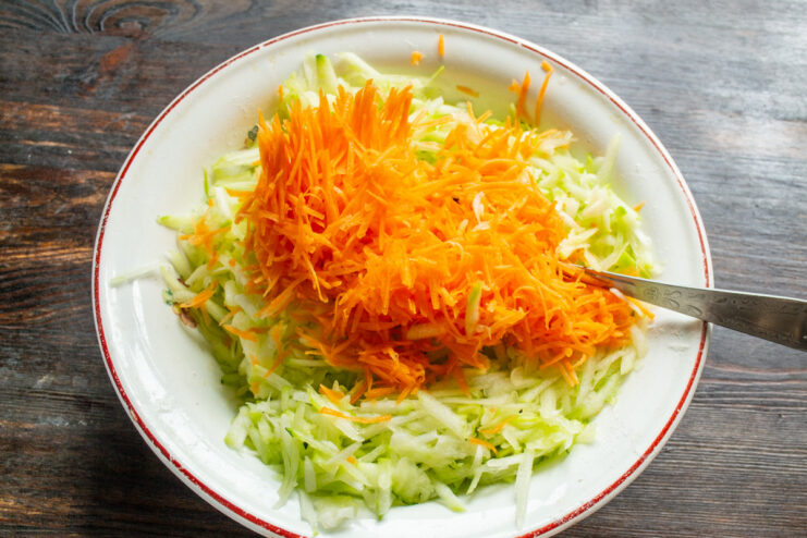 Finely Grating Carrots for Extra Flavor and Color Grating a carrot on a fine grater, adding it to the bowl with zucchini.