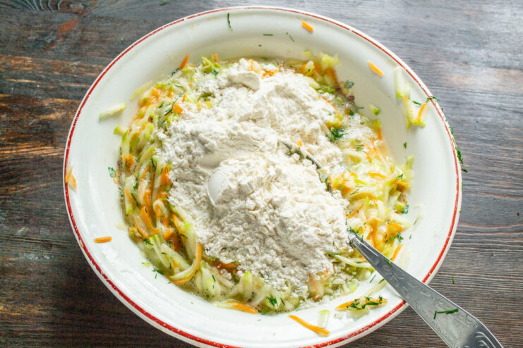 Adding Flour and Baking Powder to the Batter Sifting flour and baking powder into the vegetable mixture.