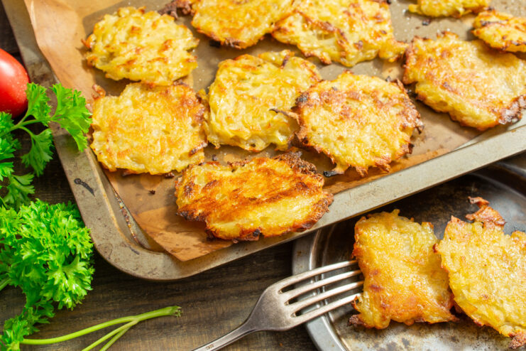 A plate of golden-brown baked potato pancakes (draniki) with onion, ready to be served.