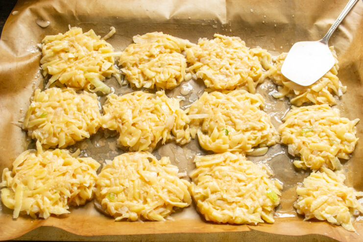 Flattening Potato Pancakes for Even Baking Using a spatula to flatten the draniki portions on a baking sheet before baking.