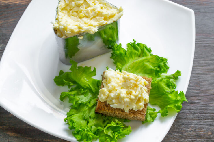Using a Cooking Ring for an Elegant Salad Presentation A cooking ring on a plate being filled with the processed cheese salad for a neat presentation.