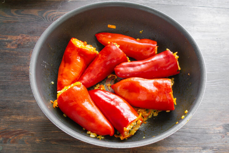Filling the Blanched Peppers with the Rice and Vegetable Mixture A hand stuffing a blanched bell pepper with a rice and vegetable filling.