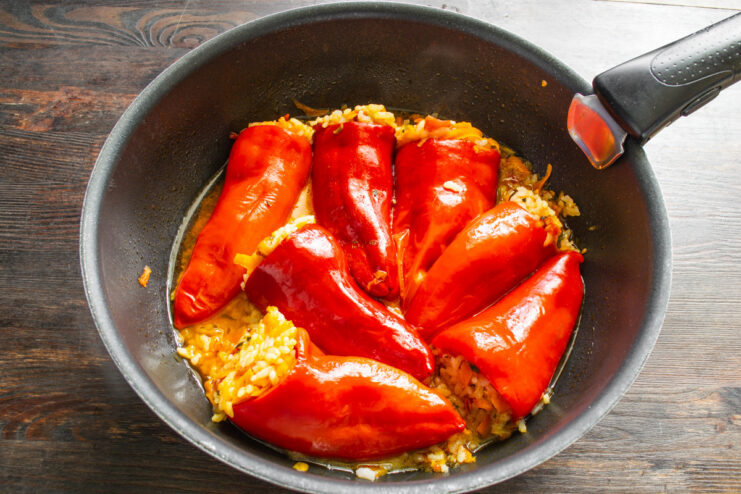 Arranging Stuffed Peppers in a Skillet for Stewing Pouring water into a skillet with stuffed peppers before stewing.