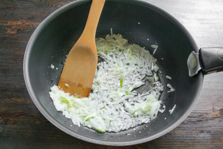 Dicing an Onion for the Vegetable Filling A hand dicing a yellow onion on a cutting board.