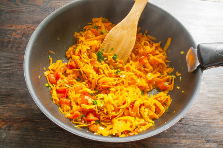 Sautéing the Vegetable Base for the Filling Sautéing a mix of onions, carrots, and tomatoes in a skillet.