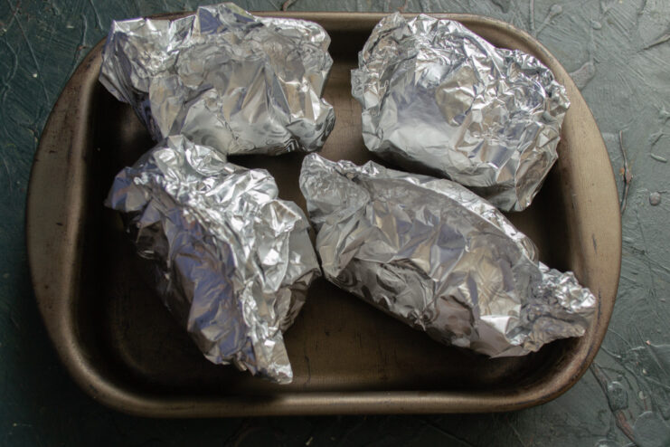 Resting the Baked Stuffed Peppers Before Serving A baking sheet with foil-wrapped stuffed peppers taken out of the oven, ready to be served.