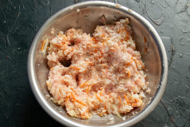 Mixing the Stuffed Pepper Filling Thoroughly A bowl of well-mixed filling for stuffed peppers, containing minced meat, rice, onion, and carrot.