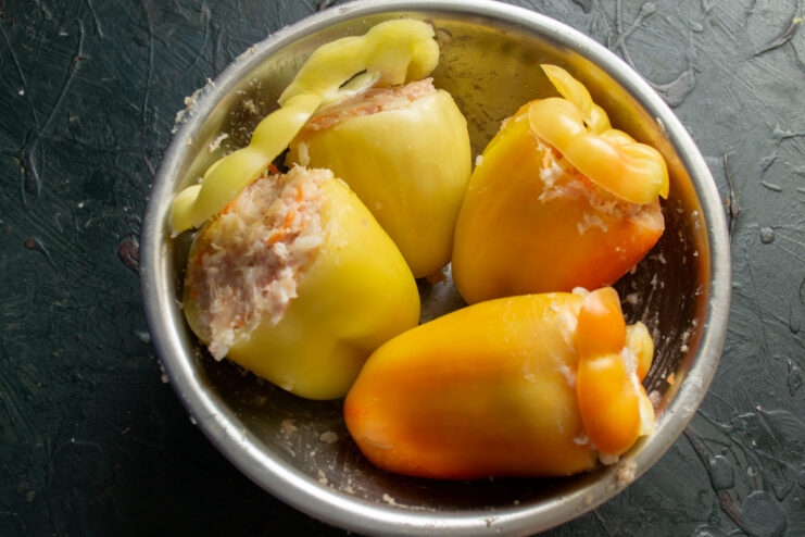 How to Stuff the Peppers and Cover with Lids Bell peppers being tightly stuffed with the meat and rice filling and covered with their tops.