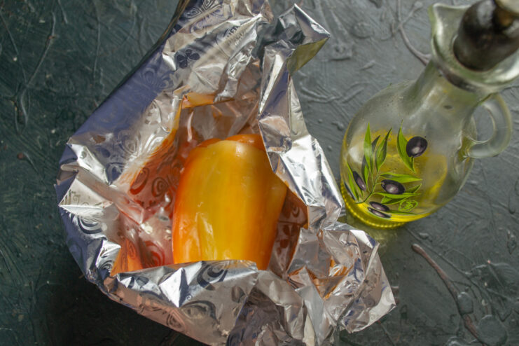 Properly Wrapping Stuffed Peppers in Foil for Baking A stuffed pepper being wrapped in aluminum foil with the edges folded up to prevent juices from leaking.