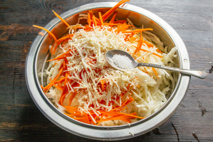 Adding Sea Salt to Start the Fermentation Process A hand sprinkling sea salt over a bowl of shredded vegetables.