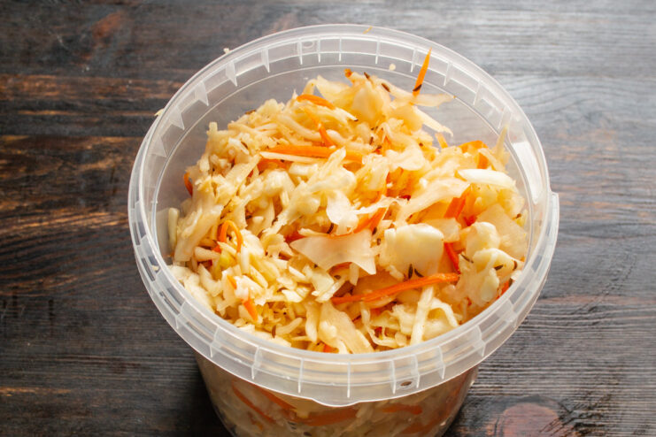 Packing the Jar and Adding Brine for Fermentation Packing the cabbage mixture into a glass jar and adding water.