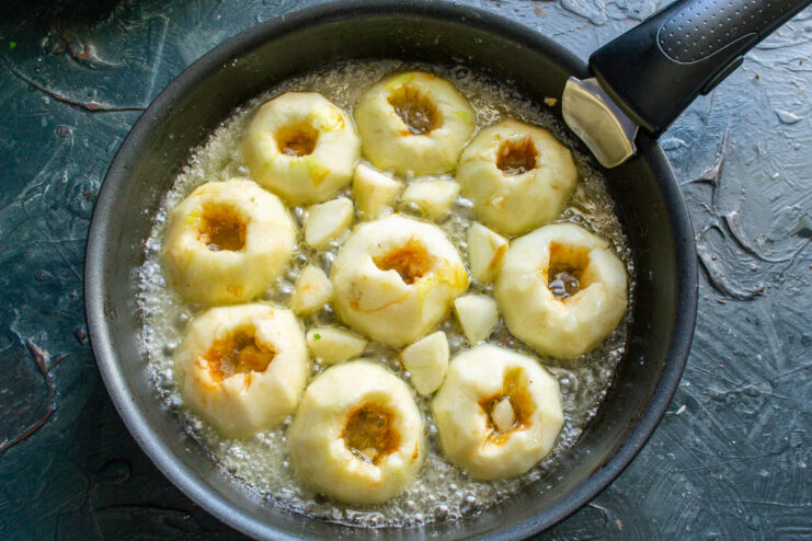 Placing Apples into the Hot Caramel Sauce Apple halves being placed cut-side down into a skillet with bubbling golden caramel.