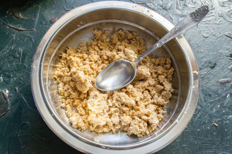 Binding the Dough with Cold Water Pouring cold water into the bowl with the flour and butter mixture to form the dough.