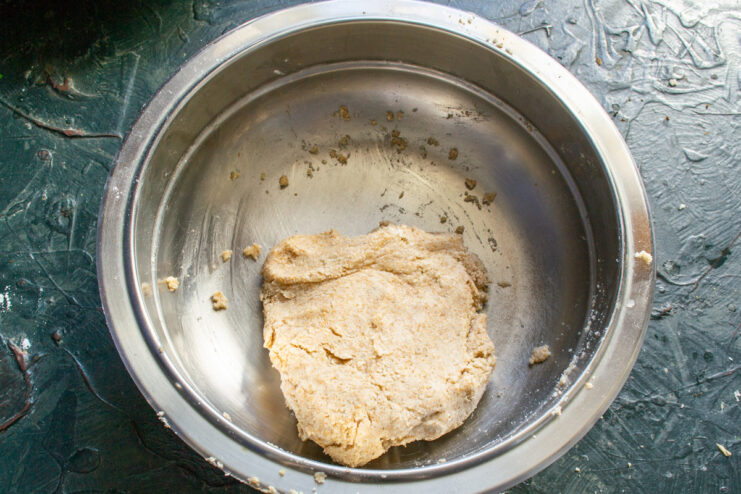 Letting the Pie Dough Rest Before Rolling A ball of dough in a bowl, covered with plastic wrap, resting on a countertop.