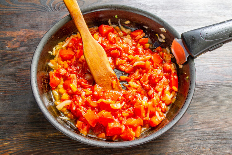 Tomato sauce simmering in a covered pan on the stove.