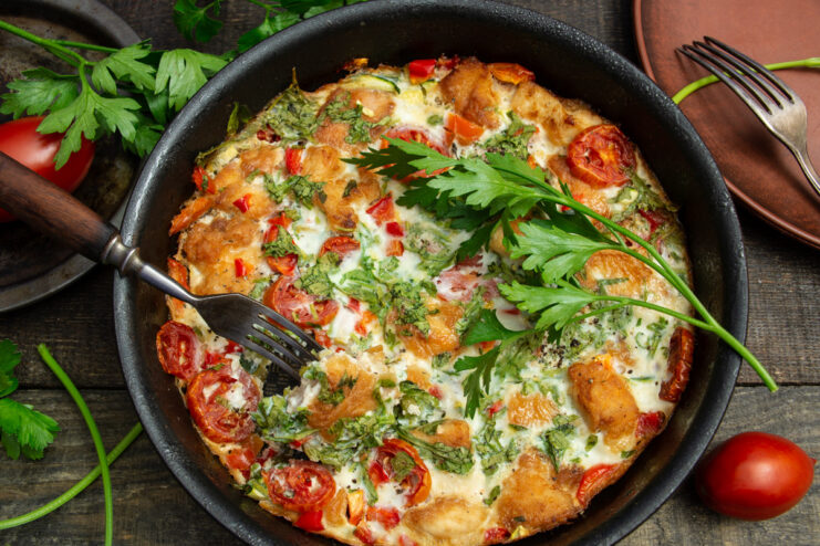 A slice of frittata with zucchini and chicken on a plate, garnished with fresh herbs.