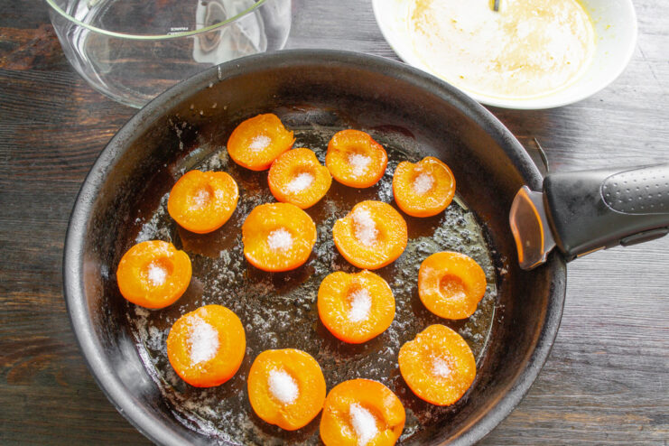 Caramelizing apricots in butter and sugar to create a delicious topping. Apricot halves being cooked in a skillet with butter and sugar.