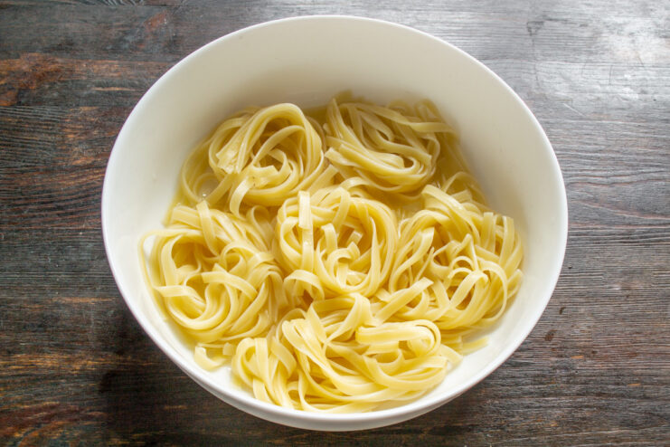 Arranging Pasta Nests in a Baking Dish Cooked pasta nests arranged in a single layer in a glass baking dish.