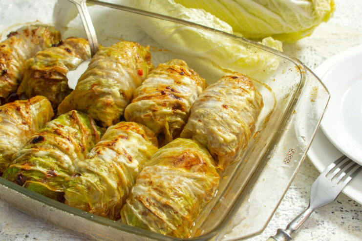 A baking dish filled with baked Napa cabbage rolls with beef and rice, ready to serve.