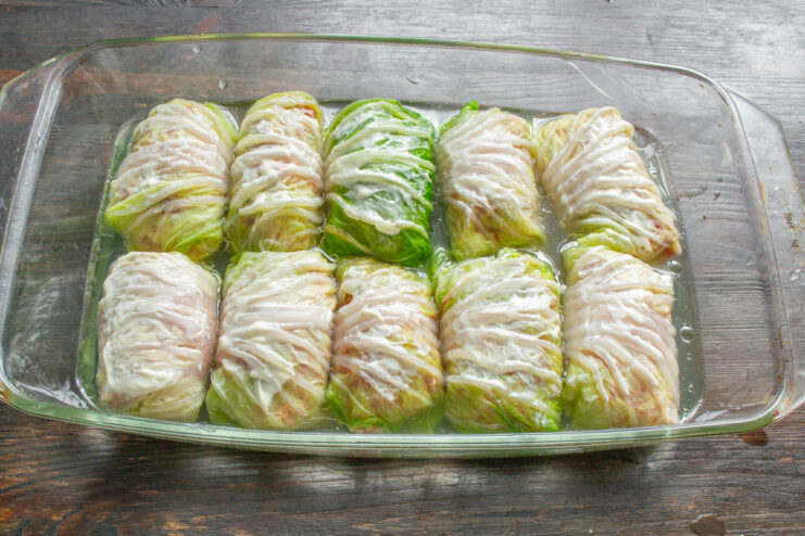 Arranging Cabbage Rolls in a Baking Dish Uncooked Napa cabbage rolls arranged tightly in a glass baking dish before adding broth.