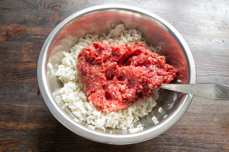 Combining Rice and Ground Beef for the Filling A bowl with cooked rice and raw ground beef being mixed for the filling.