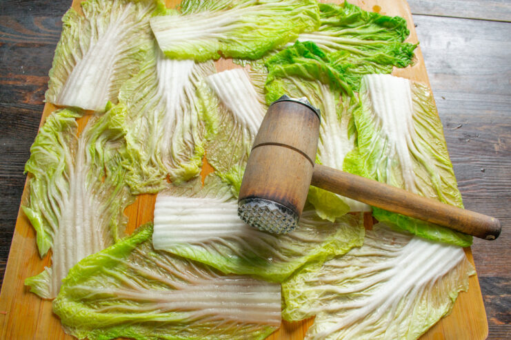 Tenderizing the Cabbage Leaves for Easy Rolling Using a meat mallet to tenderize the thick stem of a blanched Napa cabbage leaf.