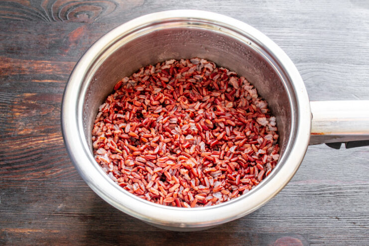 Soaking red rice overnight for a better texture. A bowl of red rice soaking in clear water.