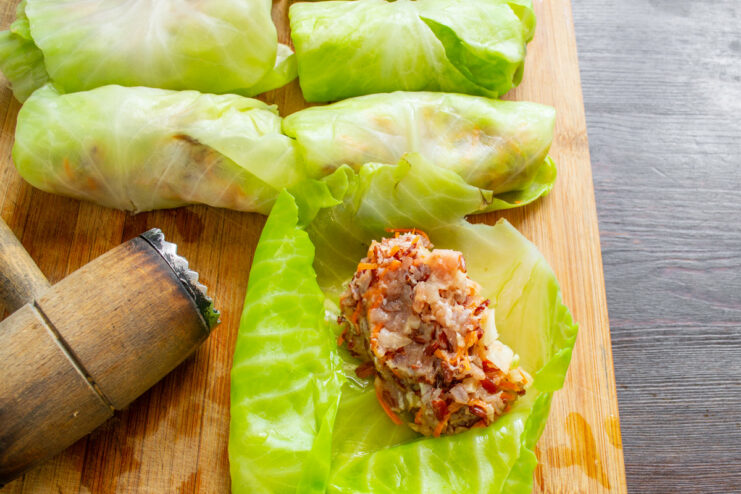 Assembling the golubtsy by placing filling on a cabbage leaf. A spoonful of meat and rice filling being placed on a blanched cabbage leaf.