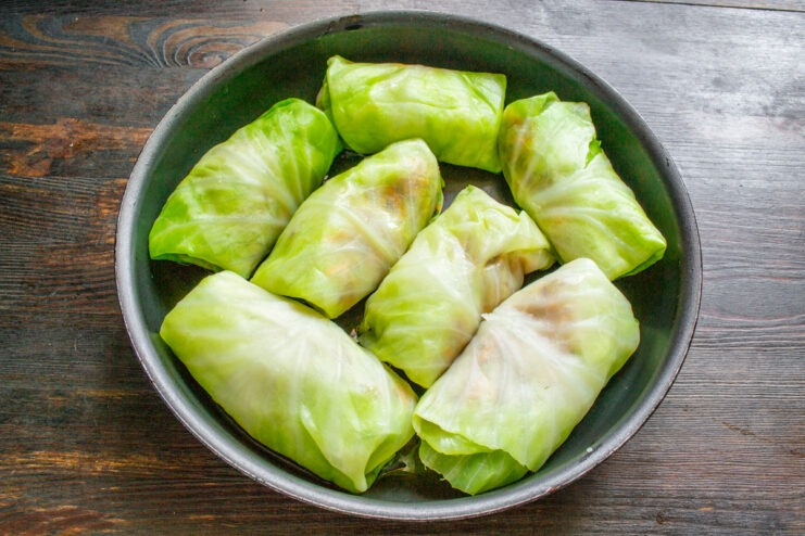 Arranging stuffed cabbage rolls snugly in a pan before cooking. Uncooked stuffed cabbage rolls (golubtsy) arranged tightly in a single layer in a large pan.