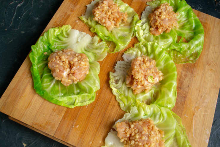 An oval patty of chicken and spelt filling placed in the center of a prepared cabbage leaf.