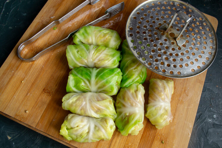 Brushing uncooked cabbage rolls and a steamer rack with oil before cooking.