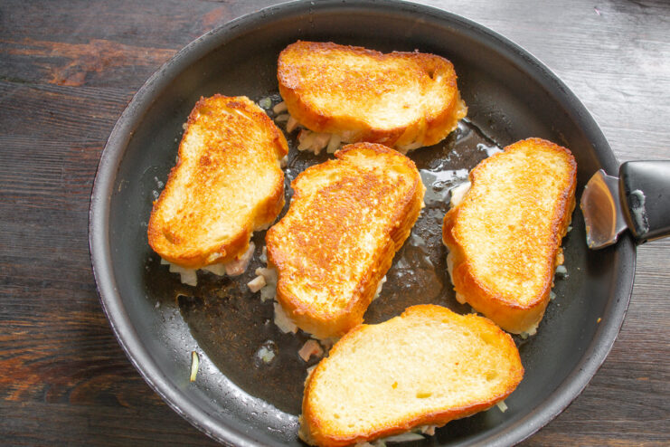 Flipping the Sandwiches to Cook the Filling Hot ham and cheese sandwiches being flipped in a skillet to cook the topping.