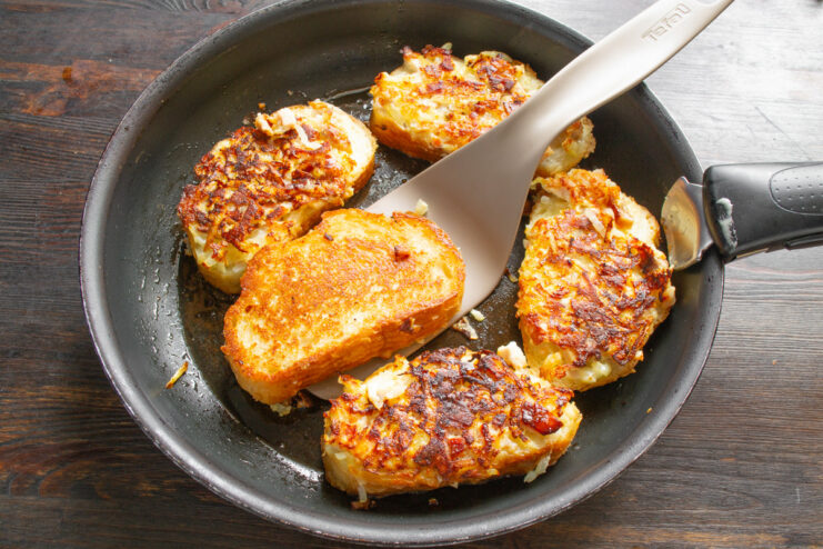 Removing Cooked Sandwiches from the Pan A spatula lifting a golden-brown hot ham and cheese sandwich from a skillet.