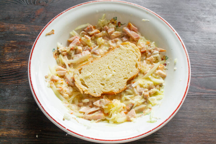Soaking the Bread in the Egg Mixture A slice of white bread being pressed into the filling mixture in a bowl.