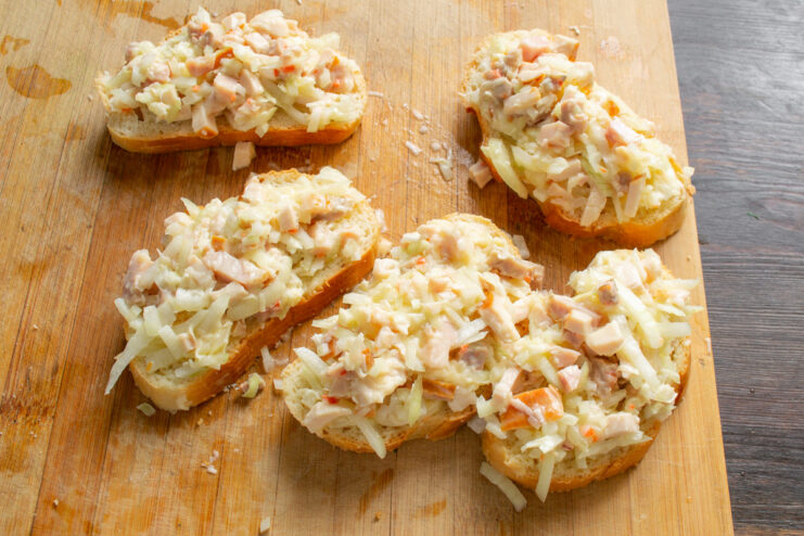 Topping the Bread with the Ham and Cheese Filling Slices of bread topped with a generous layer of ham and cheese filling.