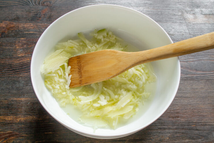 Preparing the Base: Dicing Onions for Maximum Flavor Chopped onions in a clear glass baking dish, the first step of the recipe.