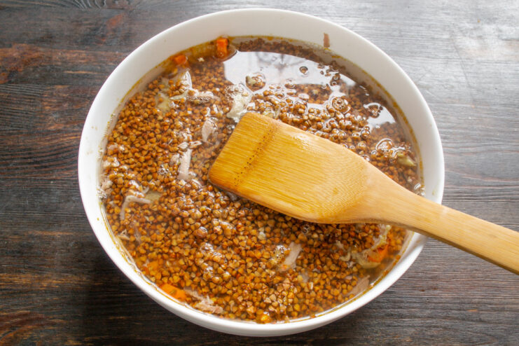 Adding Hot Water to Cook the Buckwheat Perfectly Hot water being carefully poured into the baking dish over the buckwheat and other ingredients.