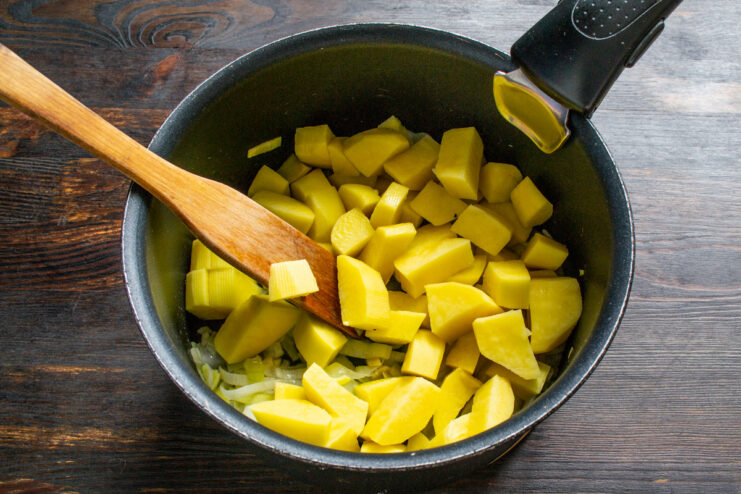 Preparing the potatoes: Dice them into small, even cubes for quick and uniform cooking. A pile of freshly diced potatoes on a cutting board, ready to be added to the soup.
