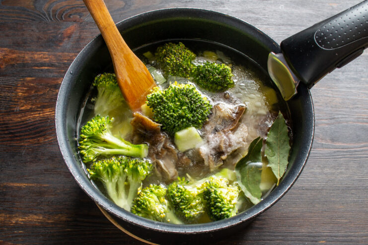 Adding liquid: Use boiling water to speed up the cooking process and maintain temperature. Pouring boiling water from a kettle into the pot with vegetables and mushrooms for the soup.