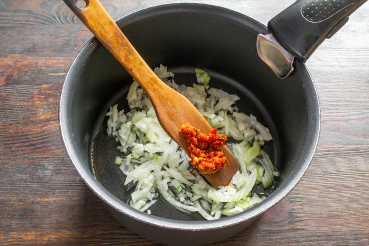Chopped onions and garlic being sautéed in a pot with oil.