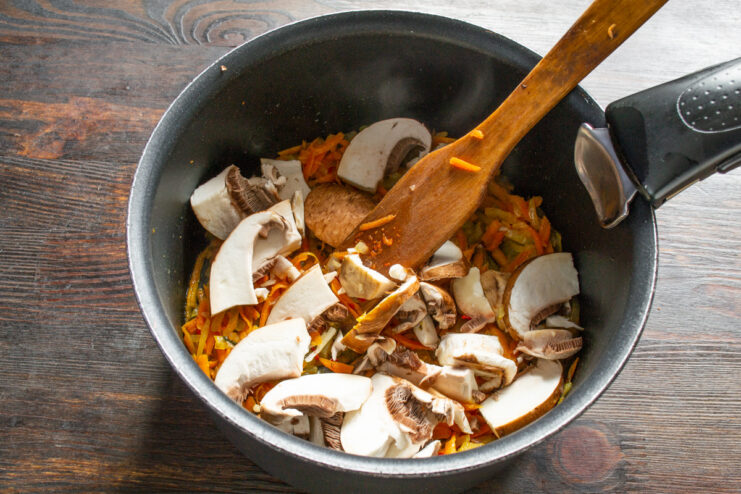 Mushroom powder and chopped cremini mushrooms being added to the pot with vegetables.