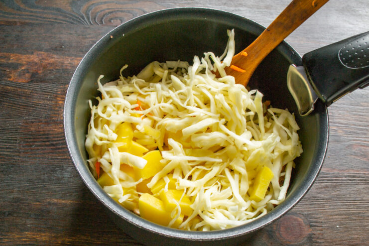 Thinly shredded white cabbage being added to the soup pot.