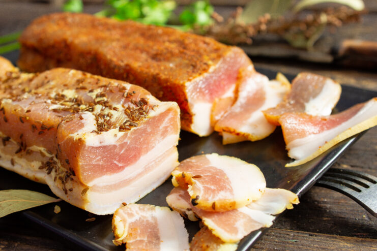 A plate of sliced salted pork belly, cured in a brine with turmeric and soy sauce, ready to be served.