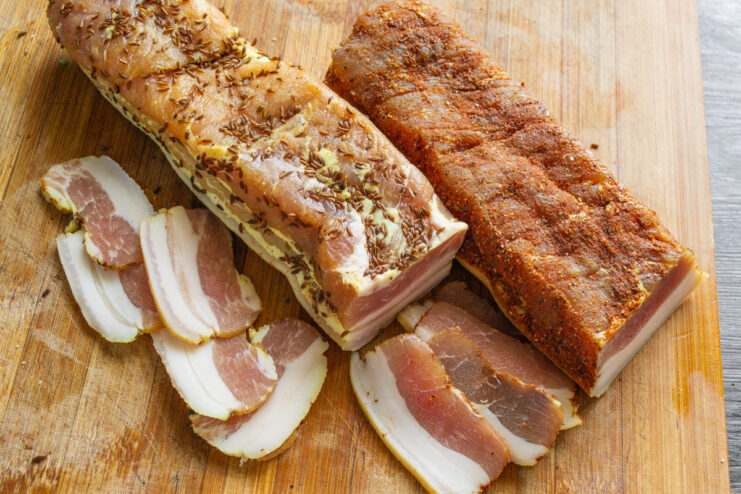 Serving the Delicious Homemade Cured Pork Belly Thinly sliced cured pork belly arranged on a wooden board, served as an appetizer.