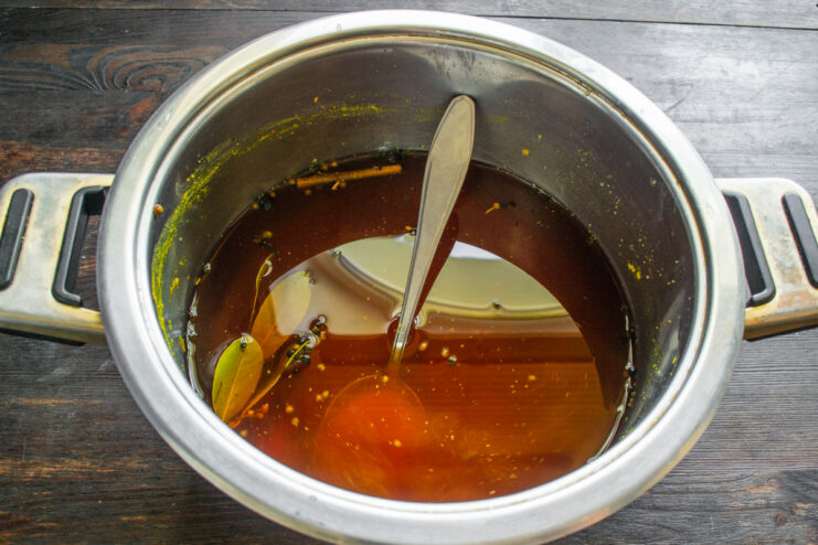 Adding Soy Sauce and Turmeric to the Brine for Color and Flavor Pouring dark soy sauce into a pot with spices and water to make a golden-colored brine.