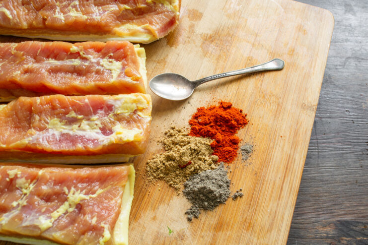 Adding a Spicy Rub for Extra Flavor A bowl containing a mix of red and black spices for coating the cured pork belly.