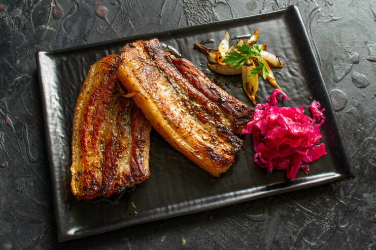 Serving the freshly cooked honey-glazed pork belly. A serving plate with freshly cooked, glistening honey-glazed pork belly, ready to eat.