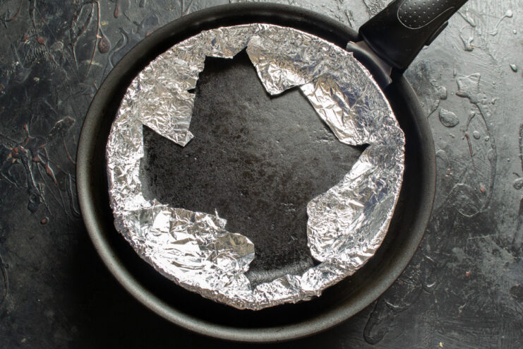 Searing the pork belly in a hot skillet under a weight. Pork belly searing in a hot skillet, pressed down with a foil-wrapped weight.