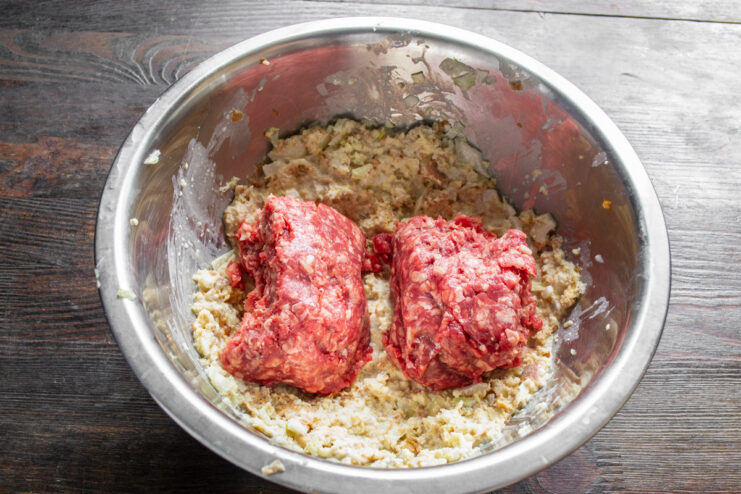 Combining Ground Beef with the Panade Mixture Chilled ground beef being added to a bowl containing a bread, milk, and onion mixture.