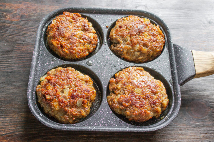 Frying Burger Patties to Golden-Brown Perfection Close-up of burger patties being fried in a pan, showing a golden-brown crust.